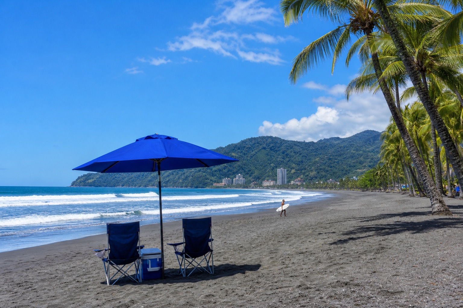 Playa Vida beach chairs and umbrella on the gray volcanic sand of Playa Jacó with palm trees and Pacific surf